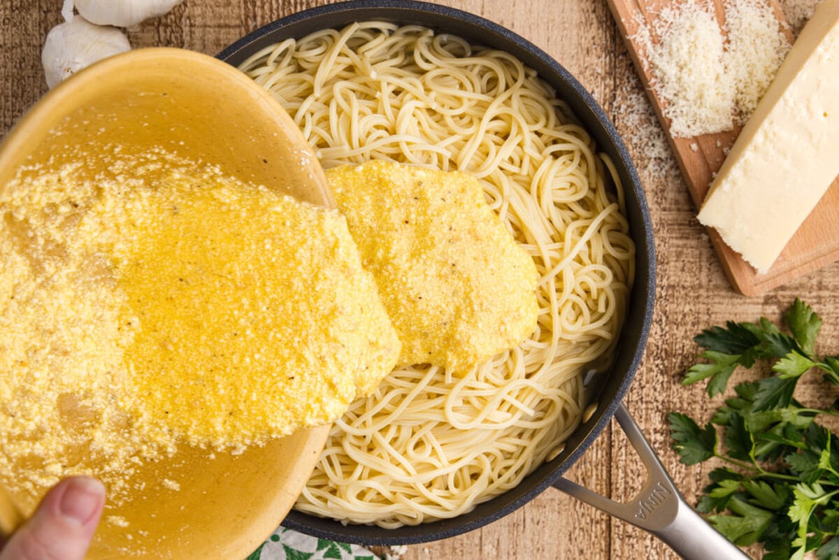 pouring egg mixture over pasta carbonara