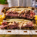 Close up photo of a Reuben Sandwich cut in half stacked on top of each other