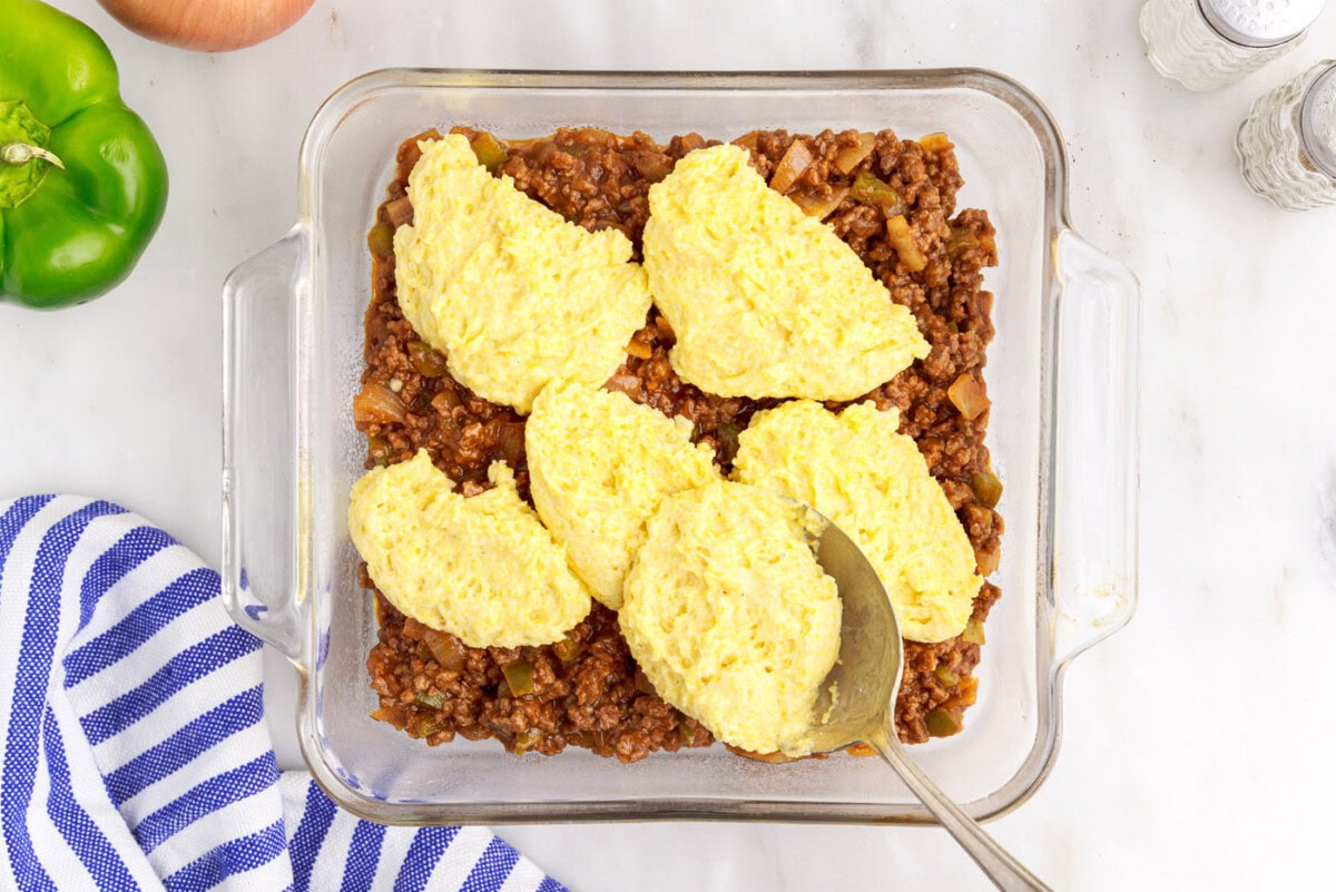 cornbread mixture over sloppy joe meat in a baking dish