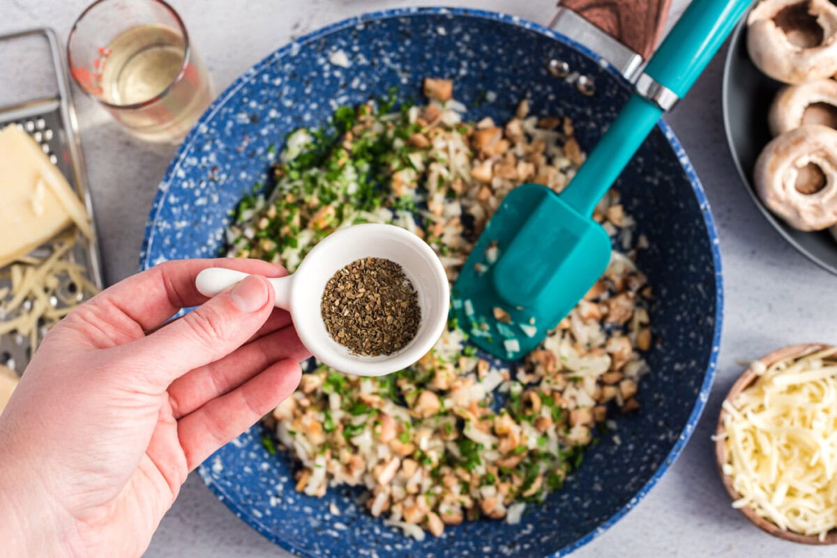 adding dried basil to onion and parsley mixture
