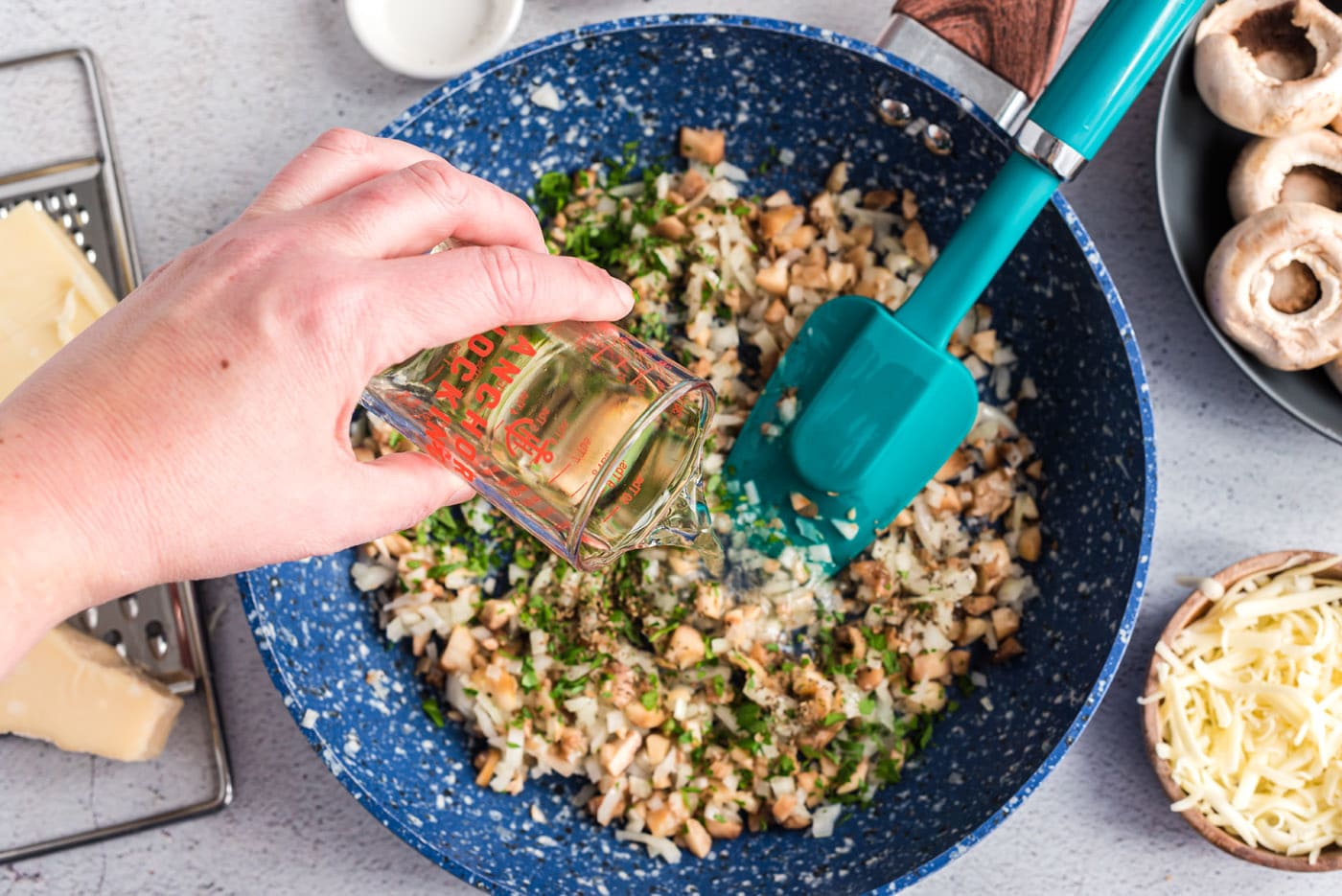 pouring vermouth into pan of onions and herbs
