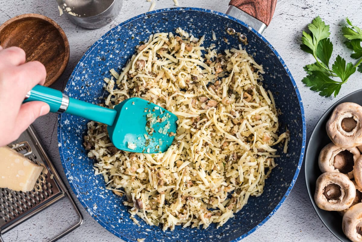 spatula stirring cheese in a pan with onion