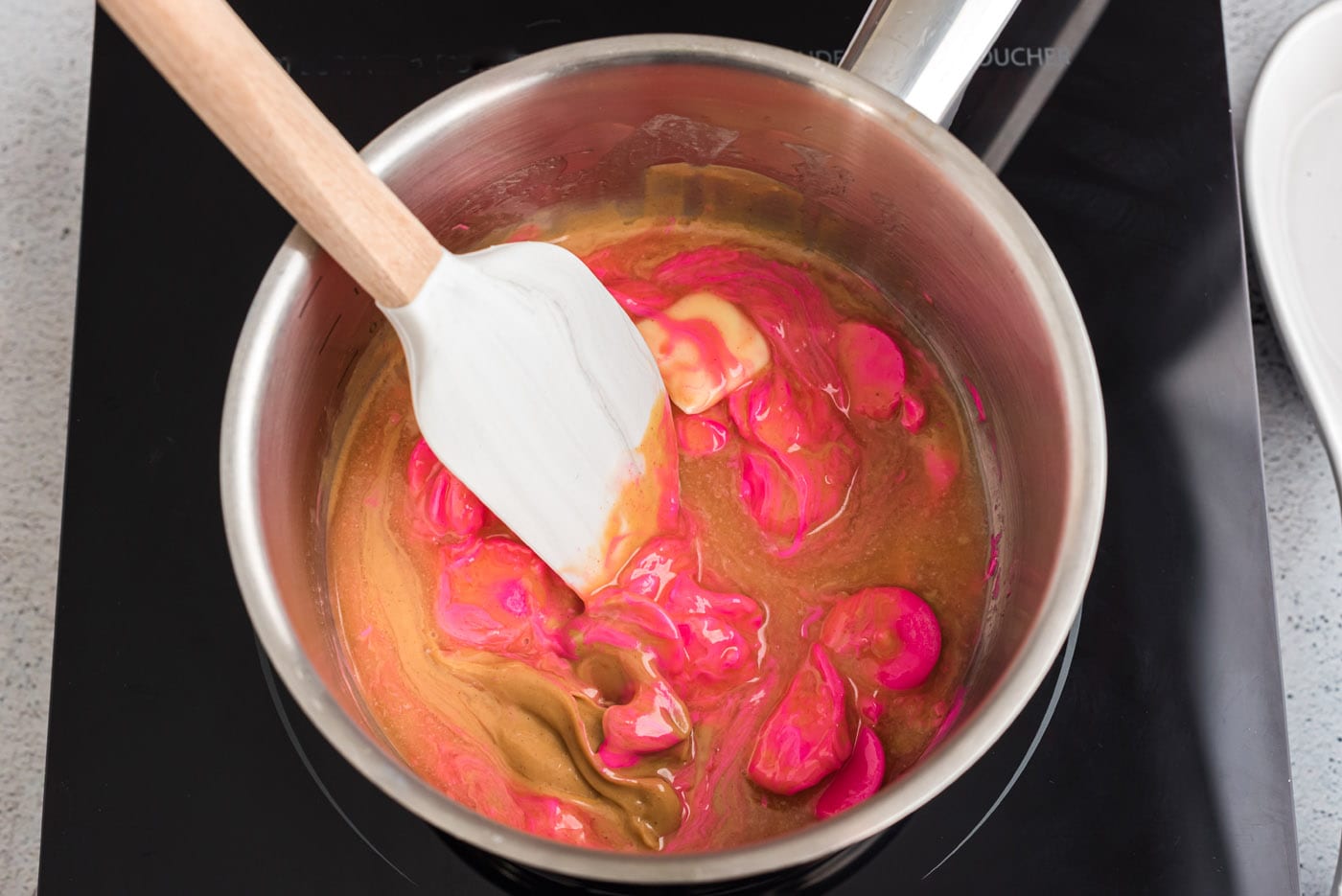 rubber spatula stirring pink candy melts with peanut butter
