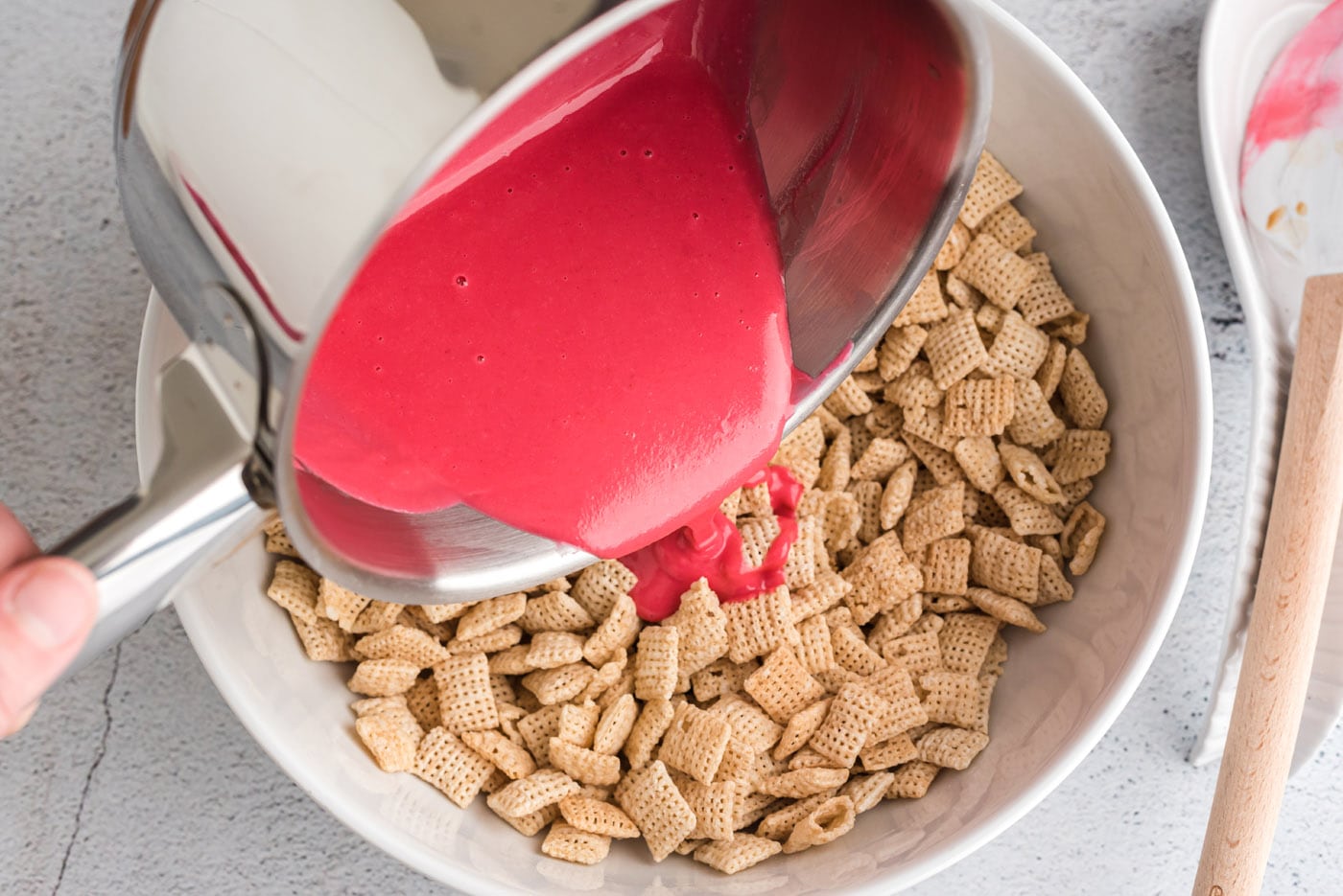 pouring pink chocolate over chex cereal