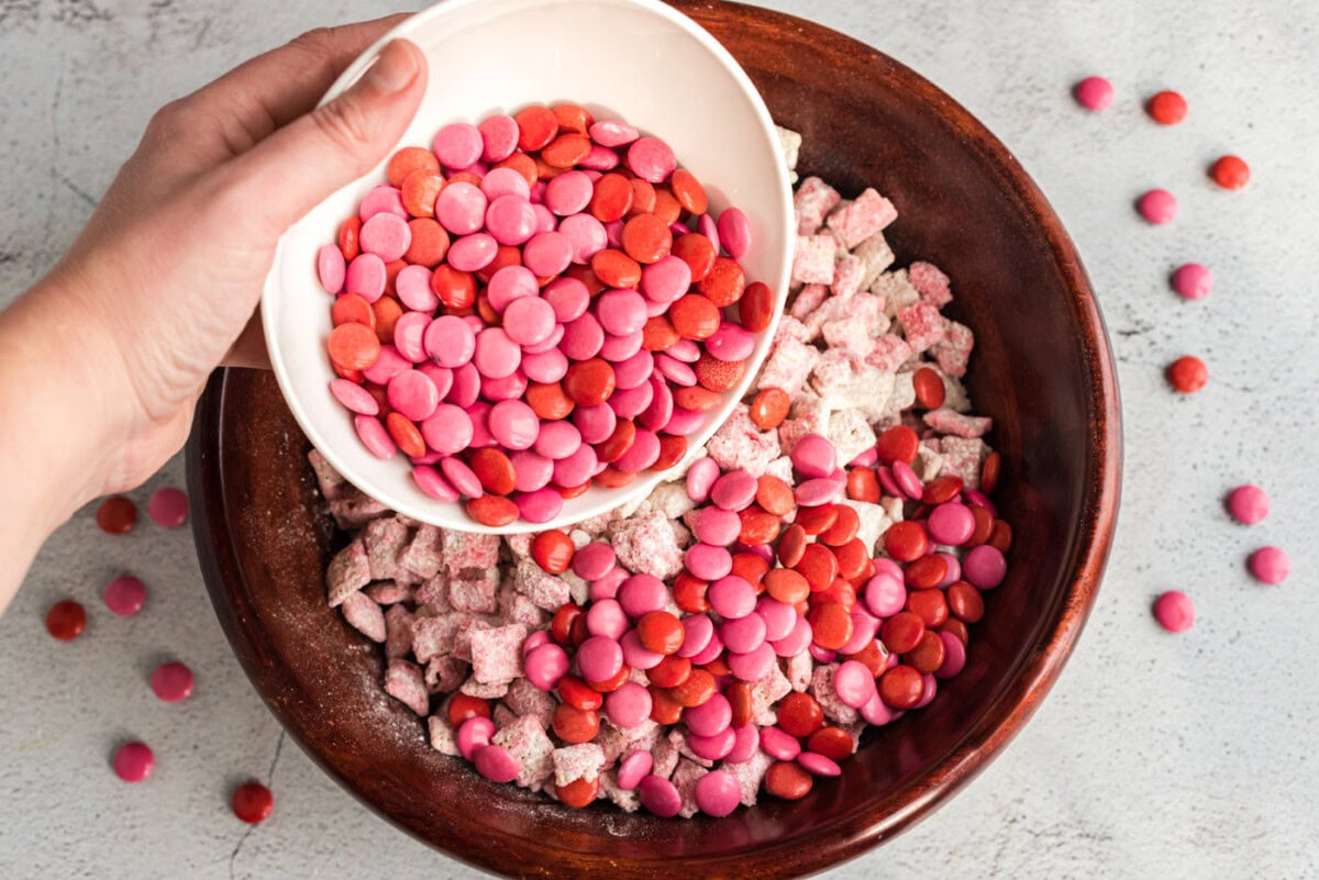 pouring pink and red M&M's into puppy chow