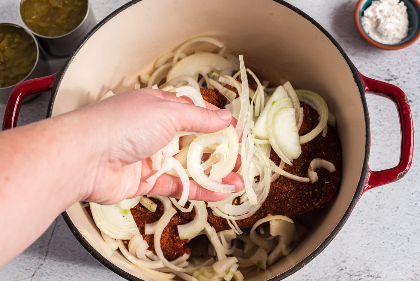 adding sliced onions to chuck roast in a pan