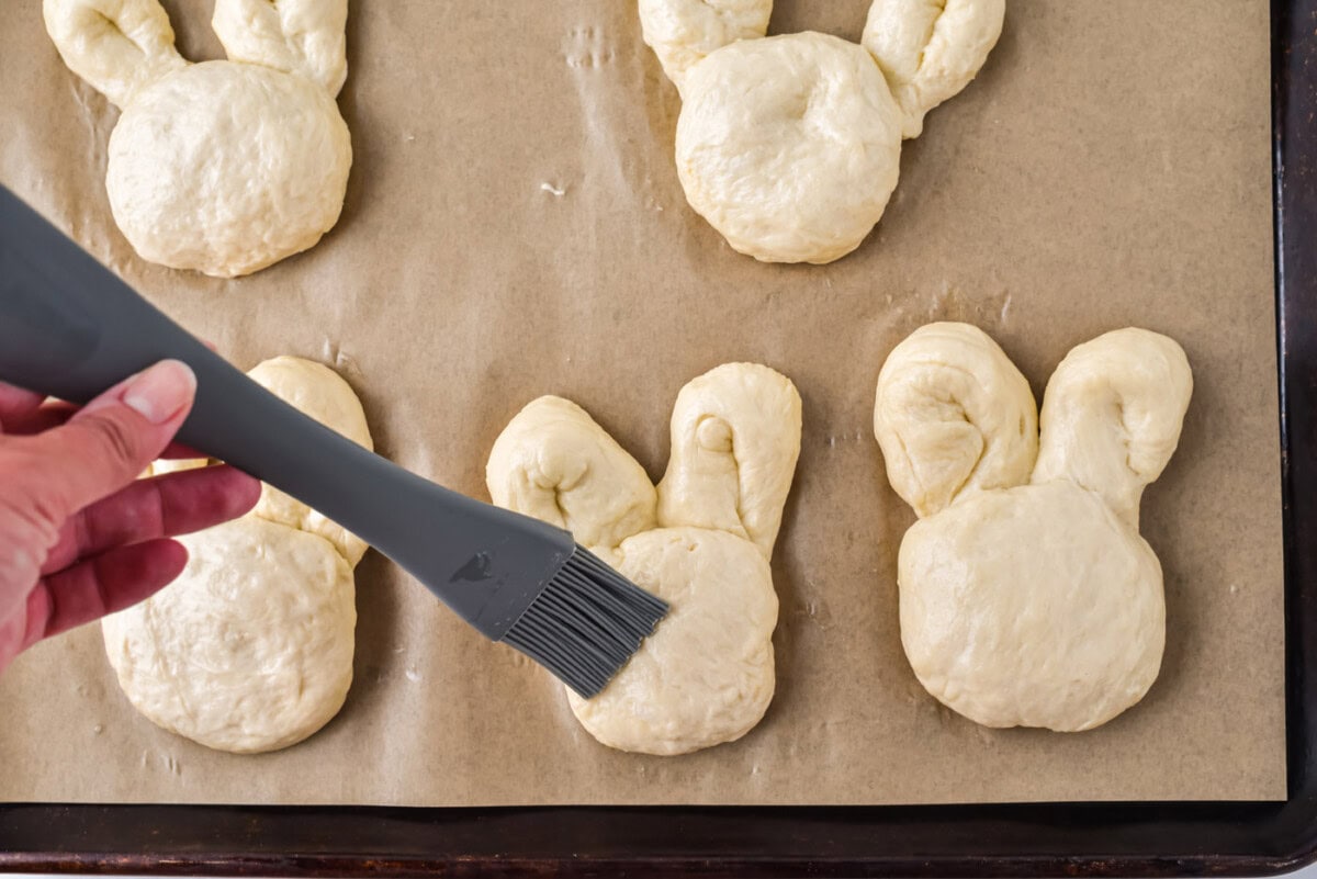 brushing bunny rolls with egg wash