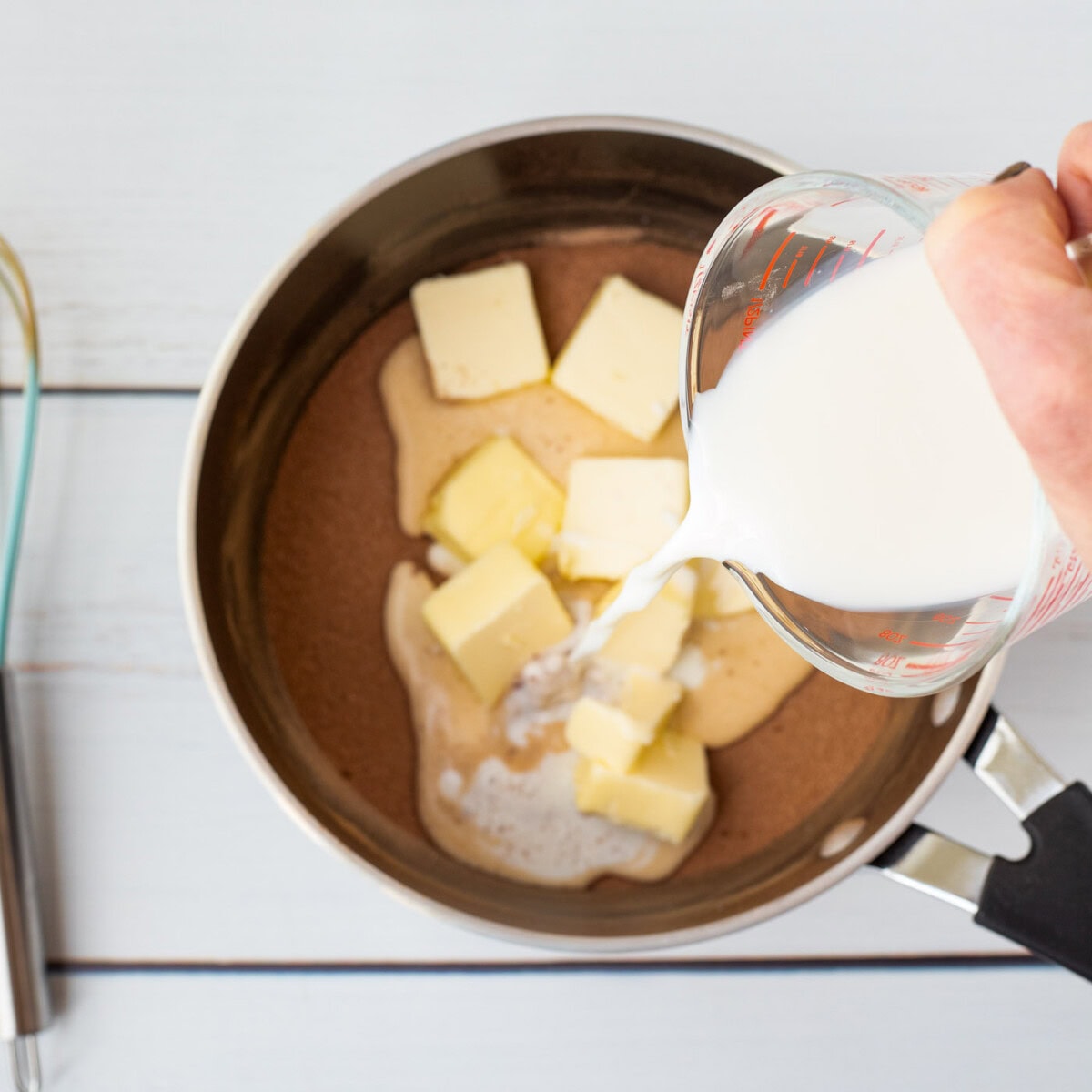 pouring milk into saucepan with butter and cocoa powder