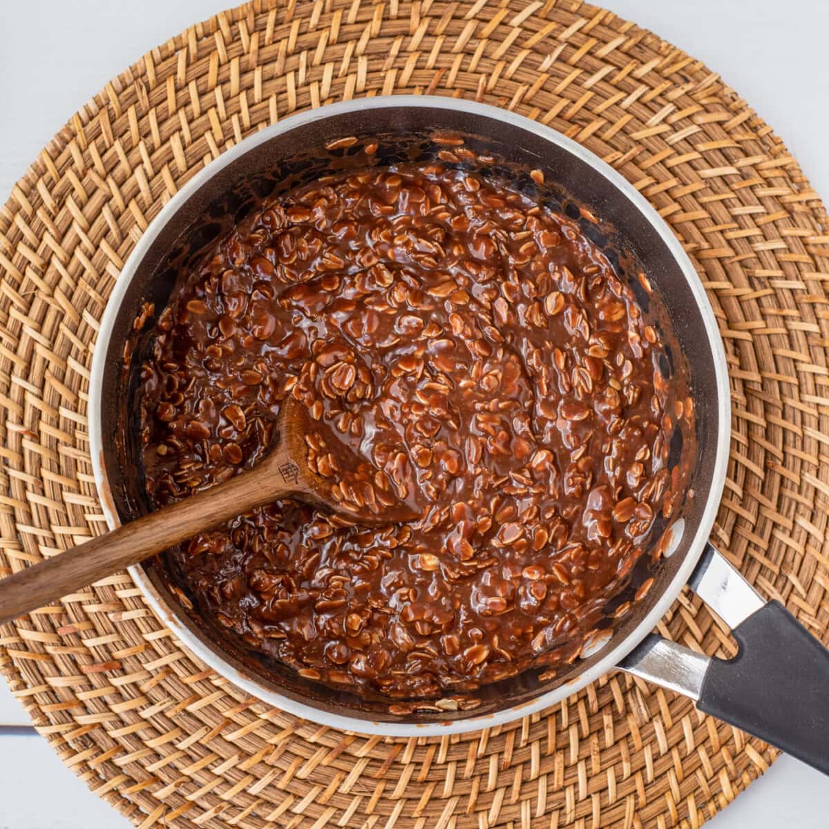 wooden spoon mixing no bake chocolate cookies in a saucepan