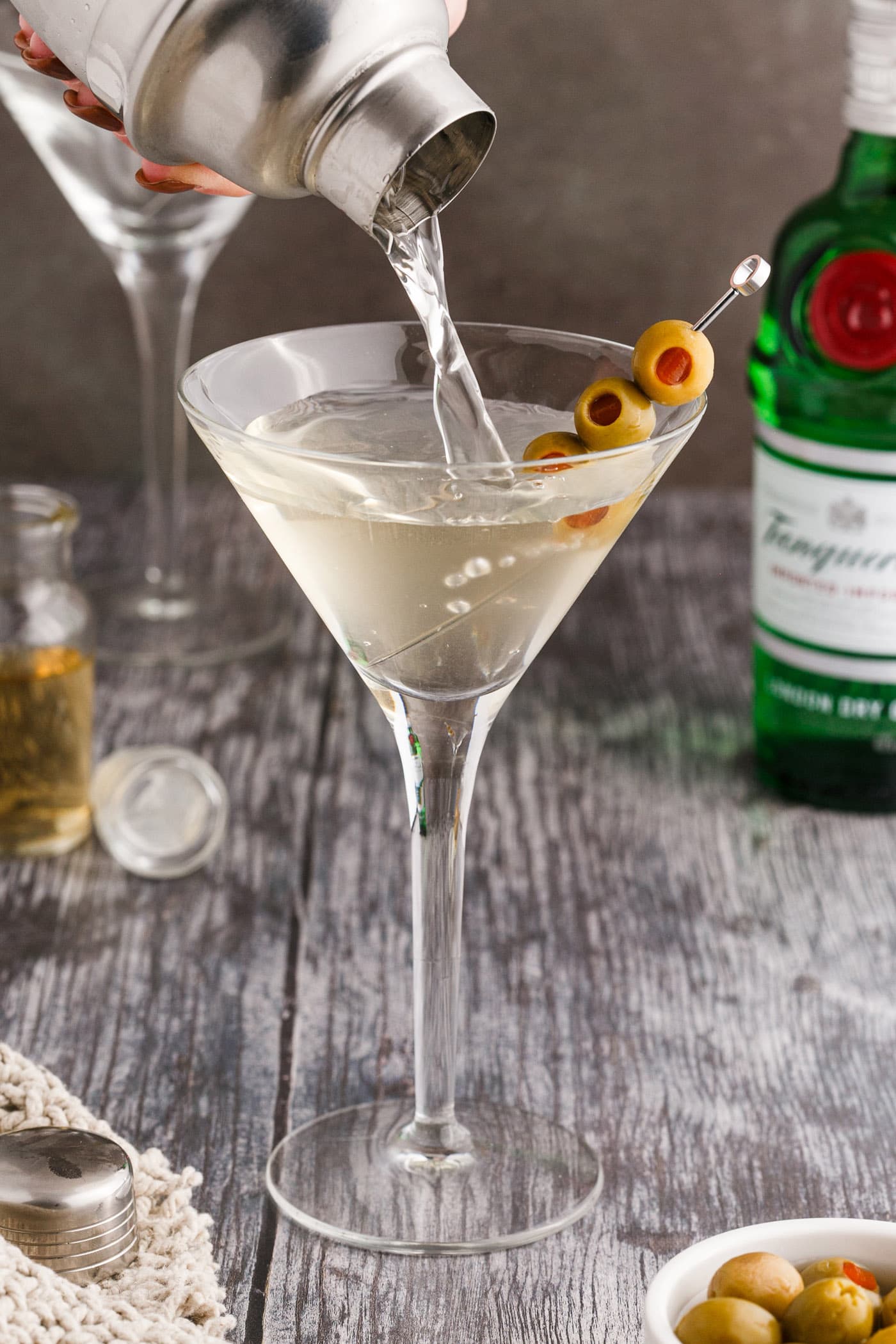 straining dirty martini into martini glass