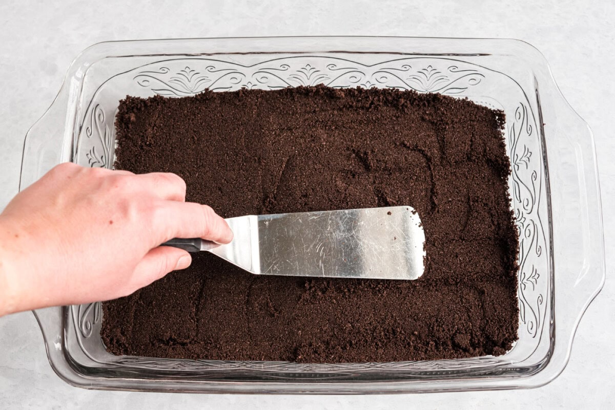 pressing oreo crumbs into a 13x9 baking dish