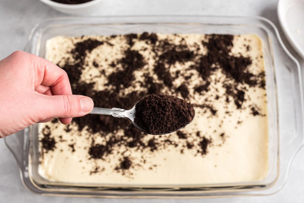 sprinkling oreo crumbs over dirt cake