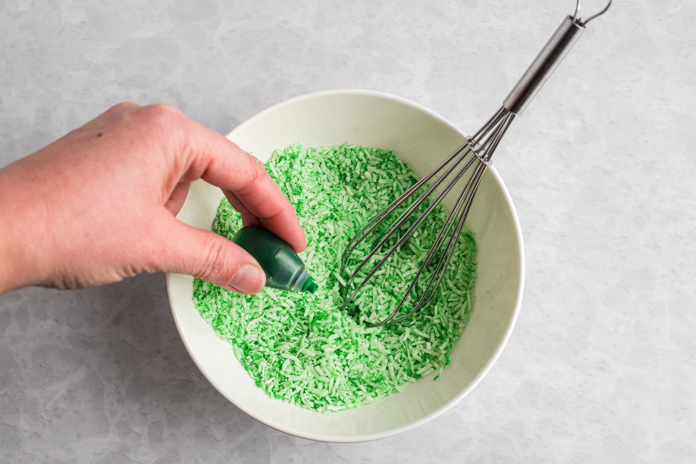 mixing green food coloring with shredded coconut