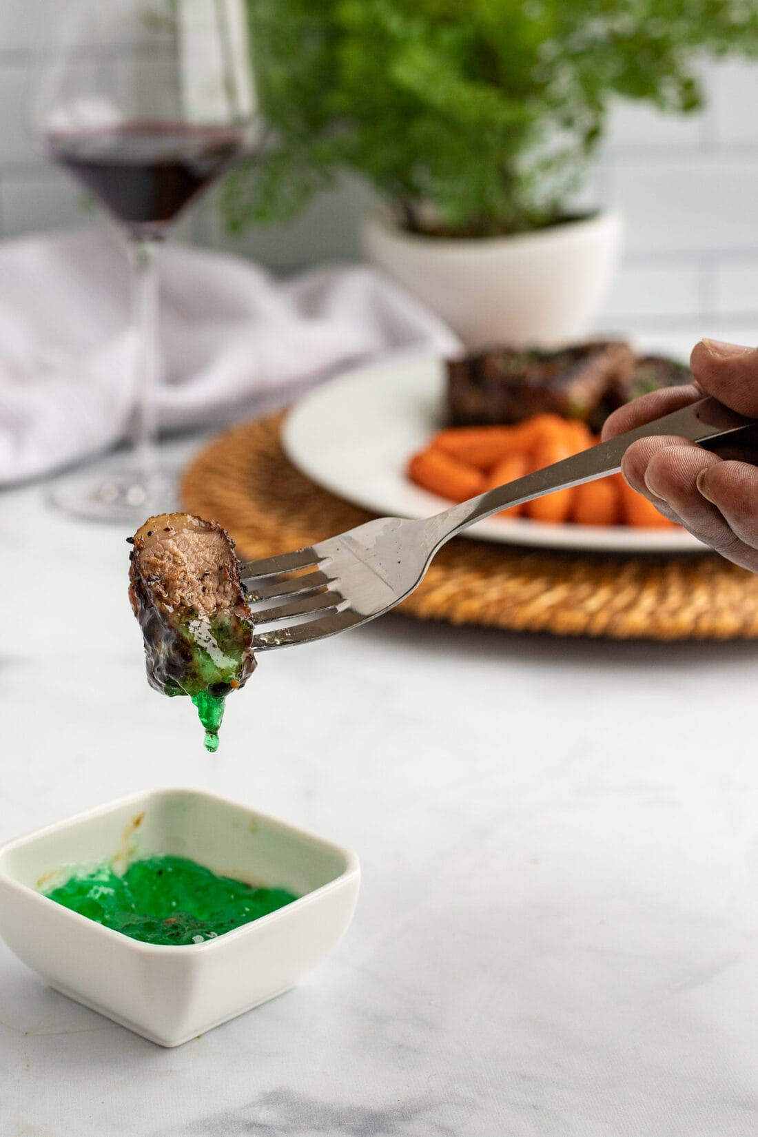 dipping fork of lamb chop in mint jelly