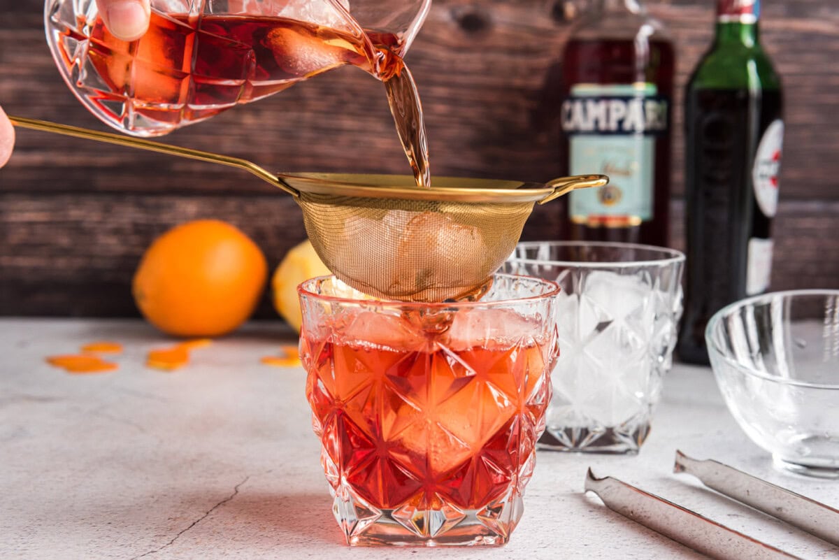 straining ingredients for Negroni into a rock glass