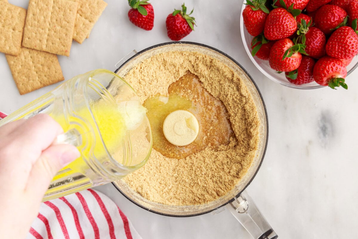 pouring melted butter over graham cracker crumbs