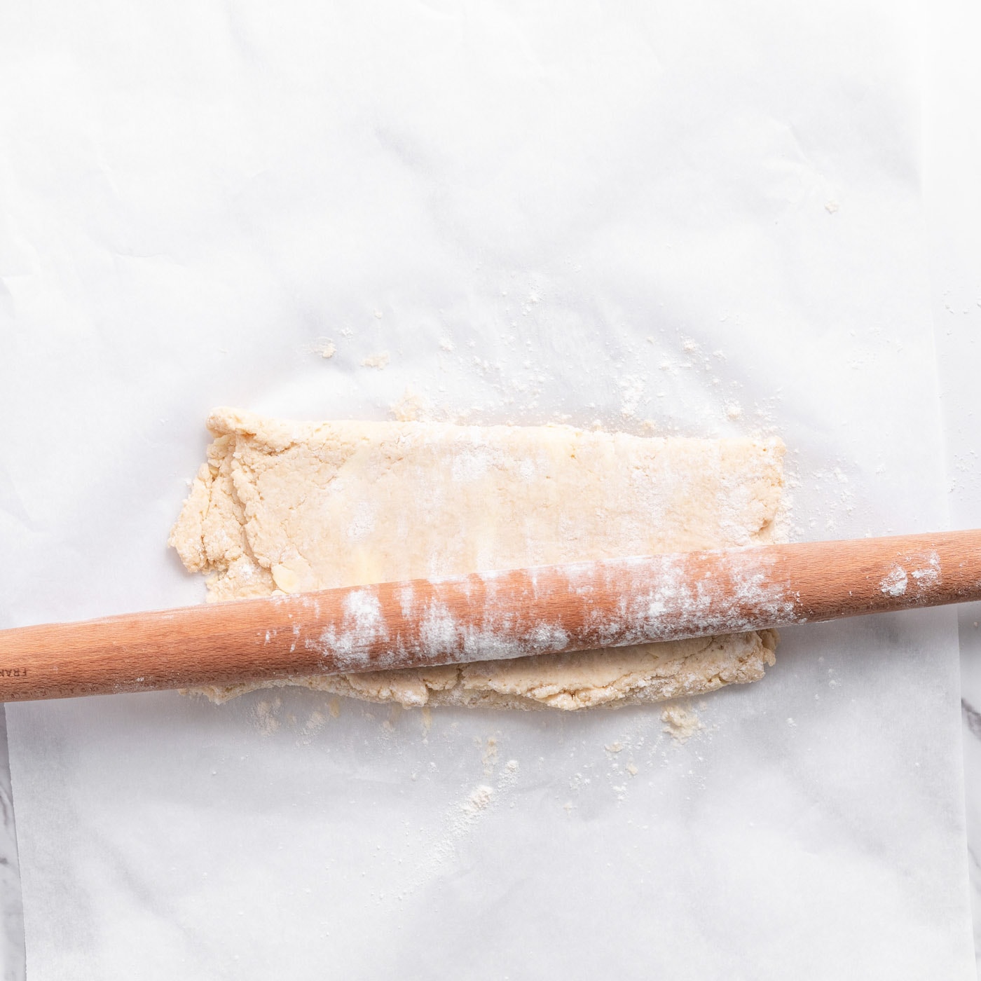 floured rolling pin pressing biscuit dough