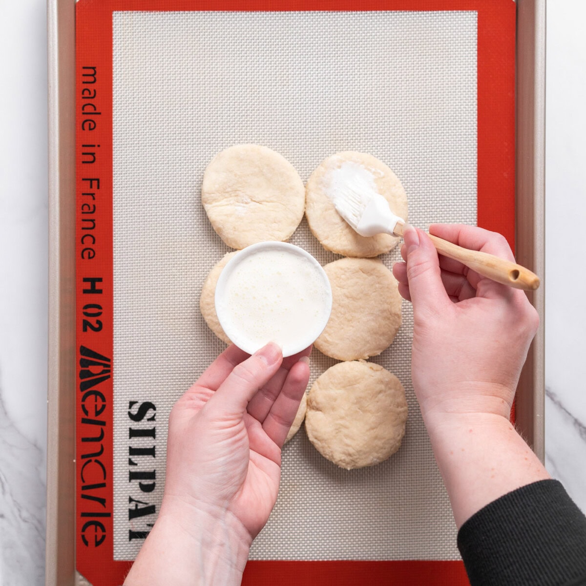 brushing biscuit dough with cream