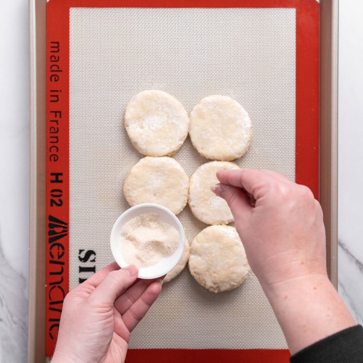 sprinkling golden sugar on biscuit dough