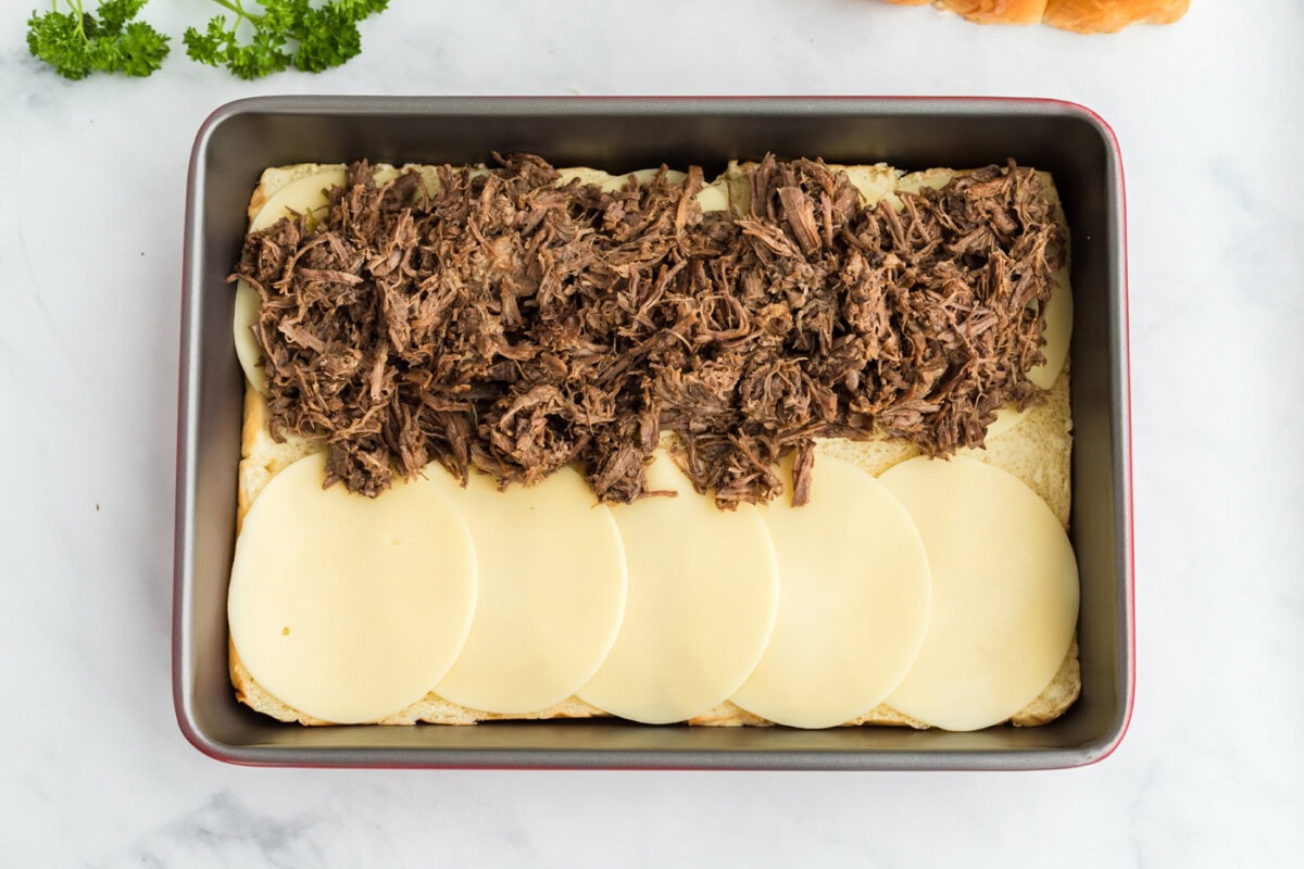 pot roast on top of provolone cheese and hawaiian rolls