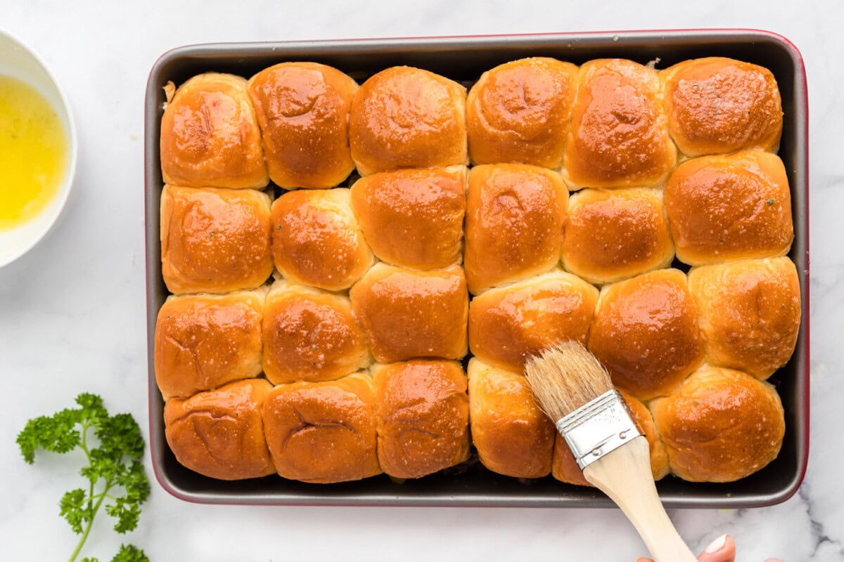 brushing on garlic butter on top of mississippi pot roast sliders