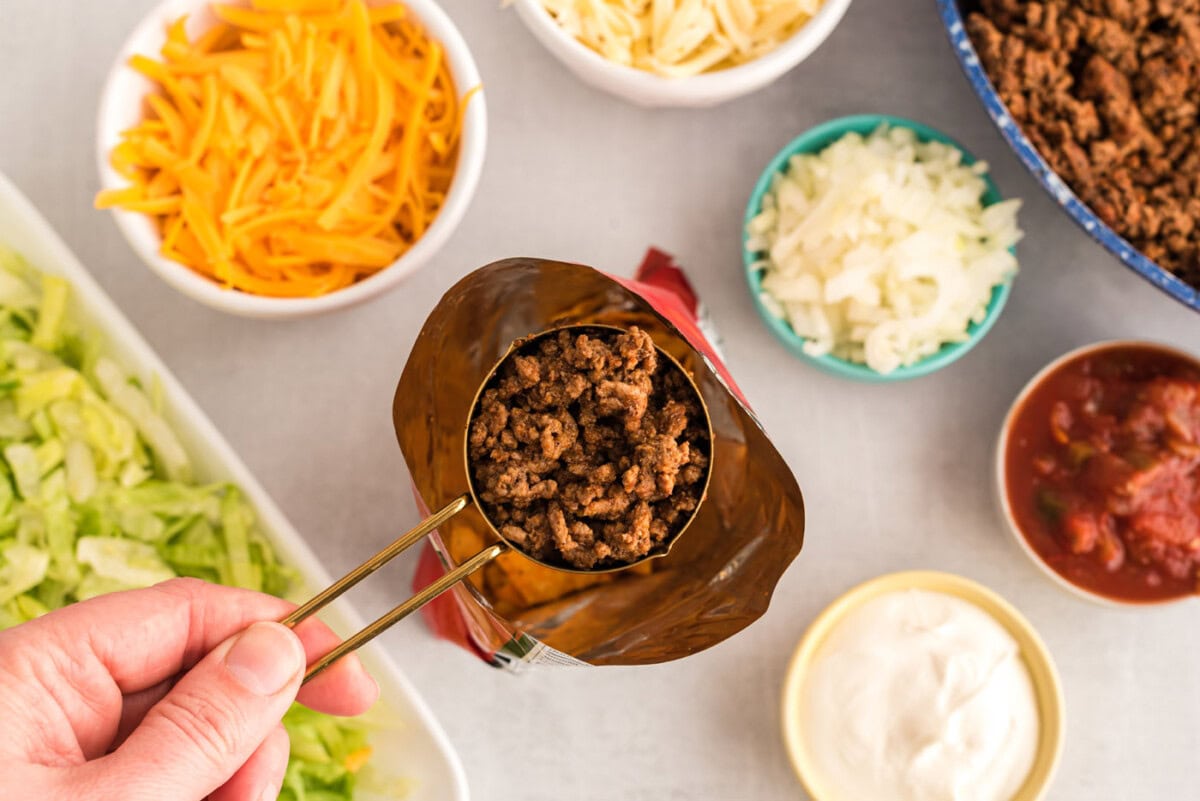 spooning taco meat into chip bag