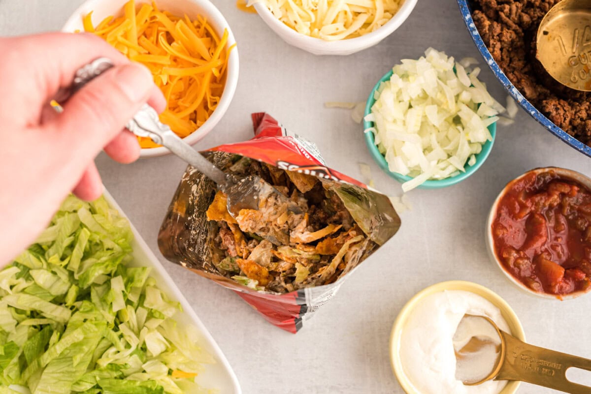 mixing taco topping into a bag of chips for walking tacos