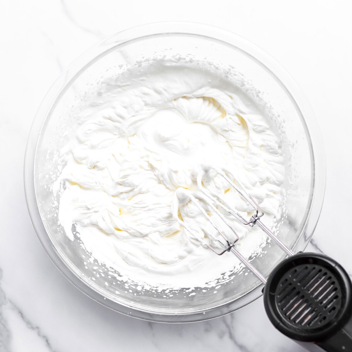hand mixer beating whipped cream in a bowl