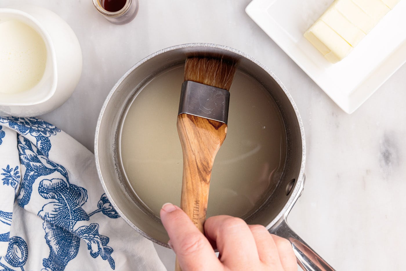 wiping down side of saucepan with a pastry brush