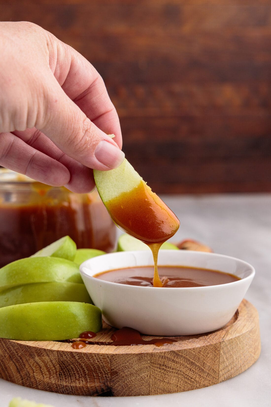 dipping apple slice into Caramel Sauce
