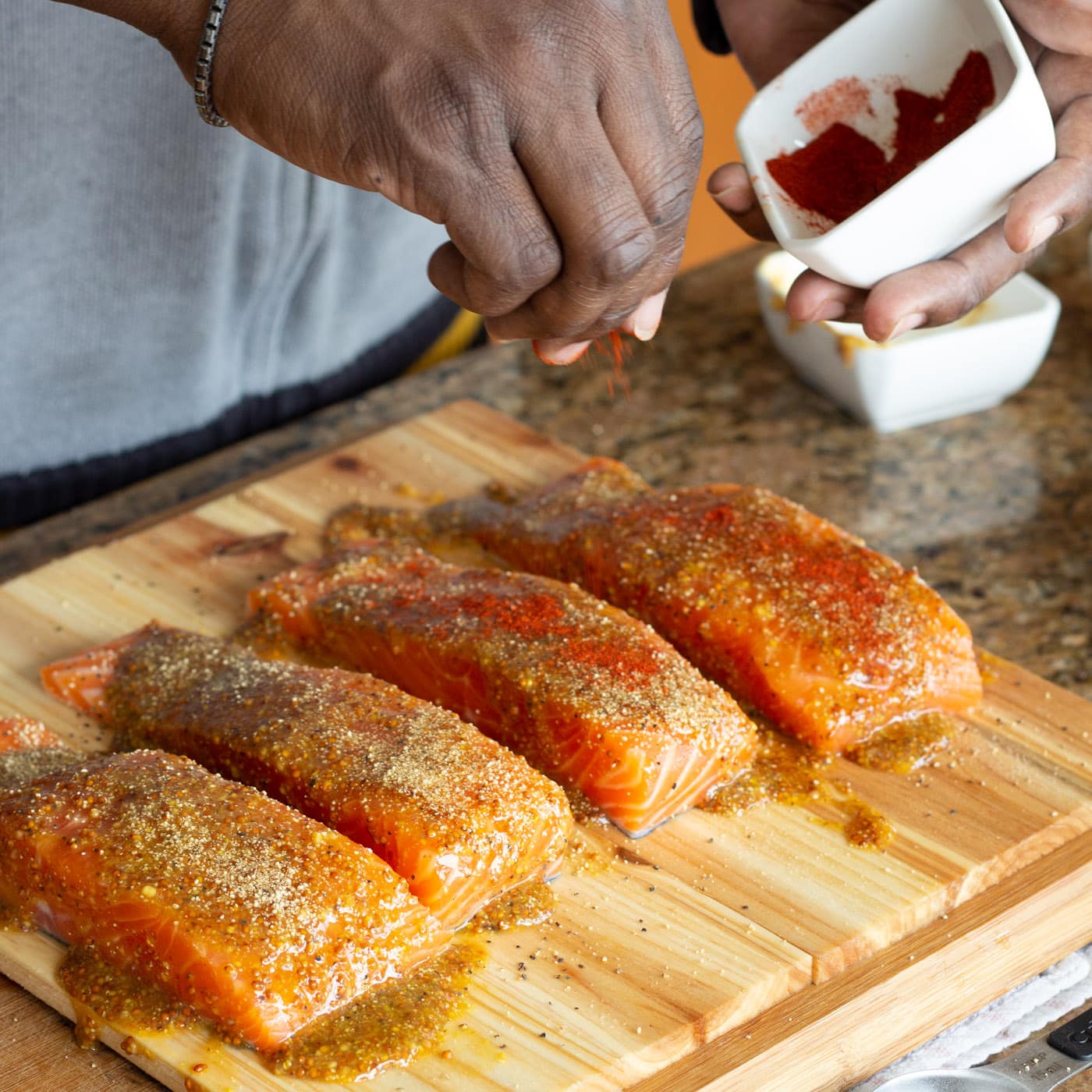 sprinkling paprika onto salmon filets