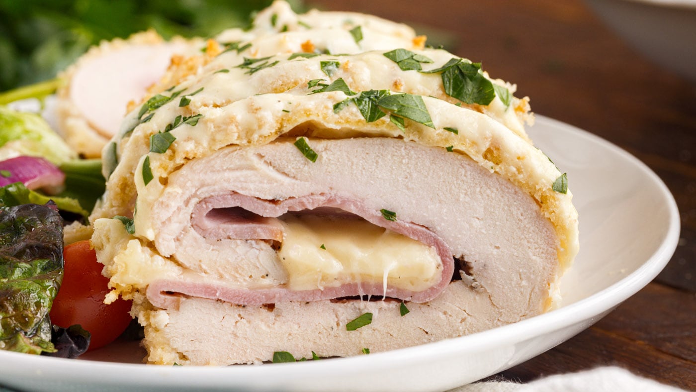 Baked chicken cordon bleu is made with ham and Swiss cheese stuffed chicken that’s rolled in seasone