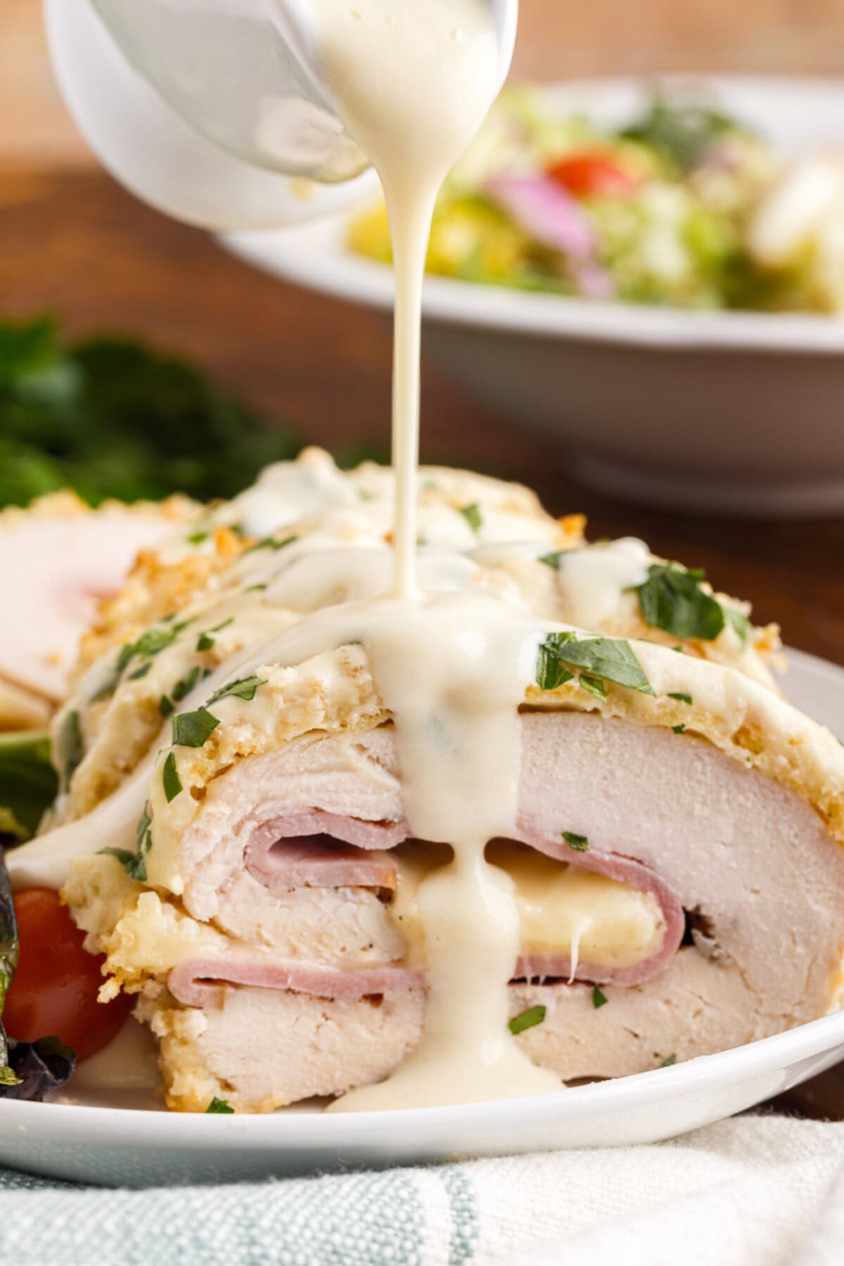 drizzling sauce on Chicken Cordon Bleu