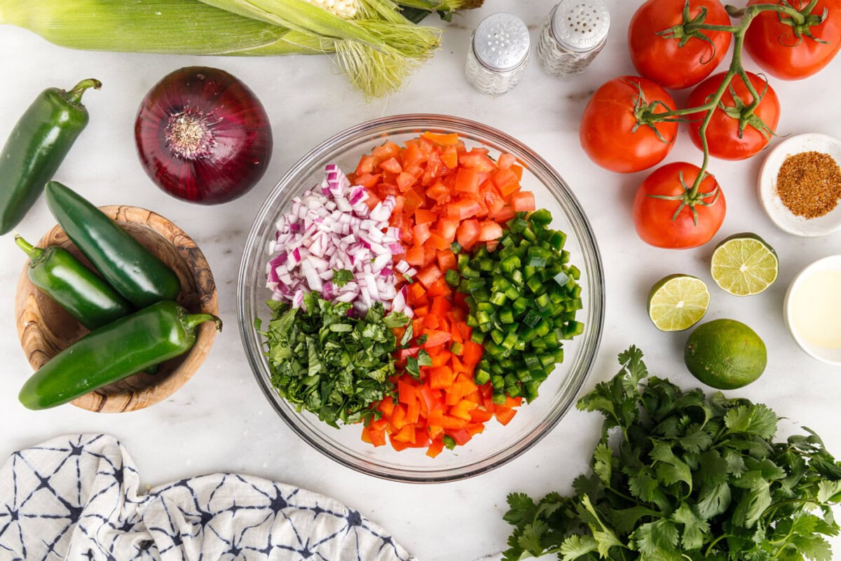 corn, tomatoes, onion, cilantro, and bell peppers in a bowl
