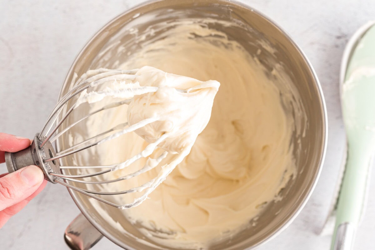cream cheese frosting on a whisk of a mixer