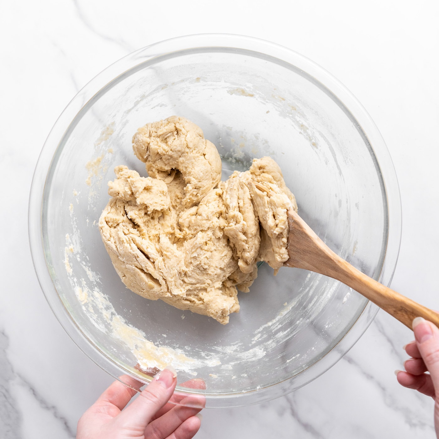 bread dough in a bowl with wooden spoon