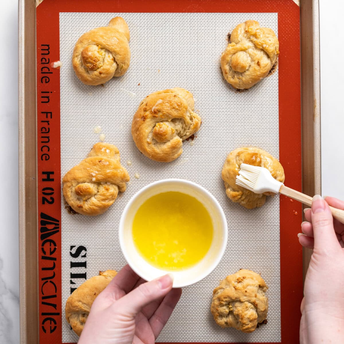brushing extra garlic butter on top of garlic knots
