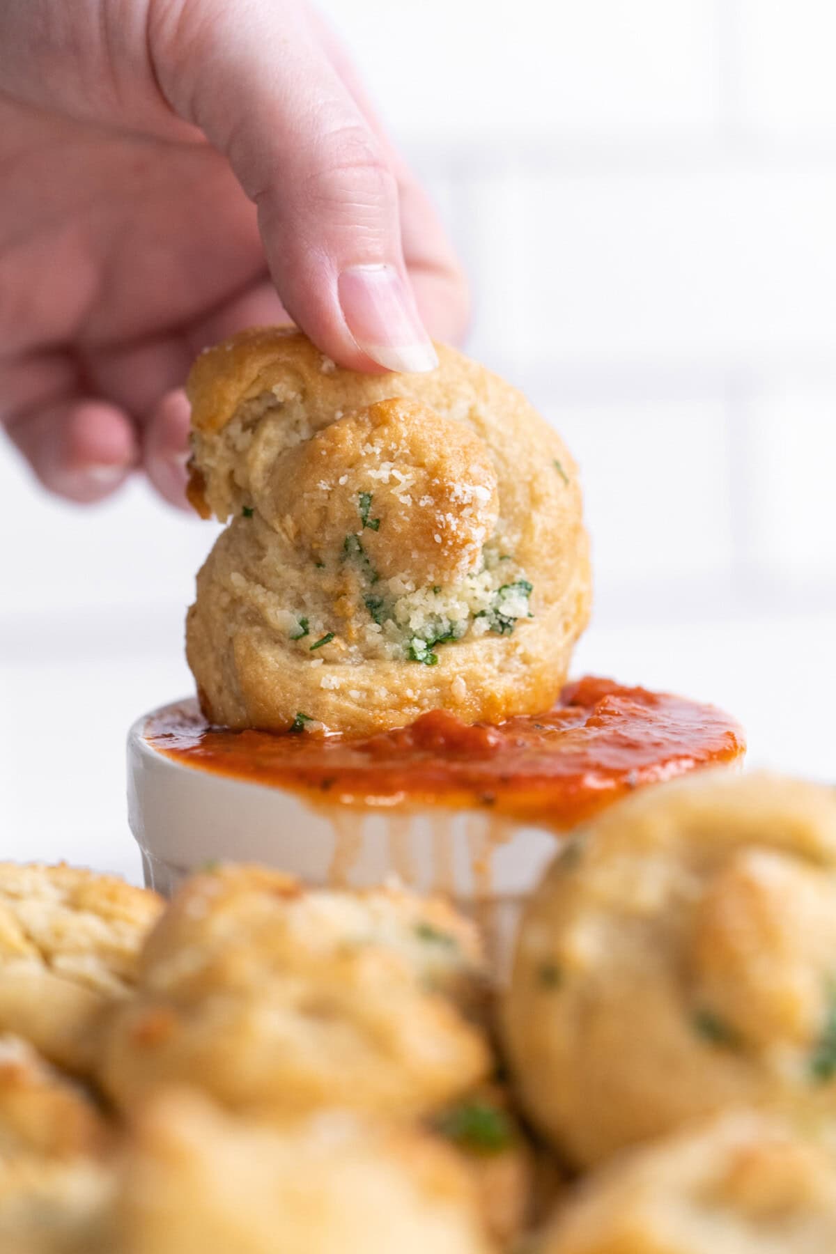 dipping a garlic knot into marinara 