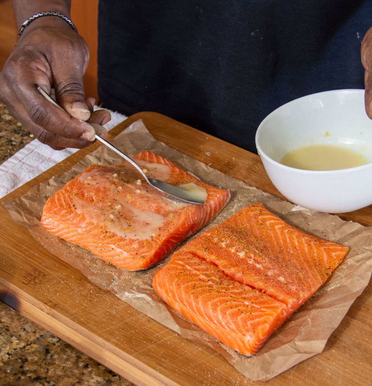 spooning lemon marinade over salmon