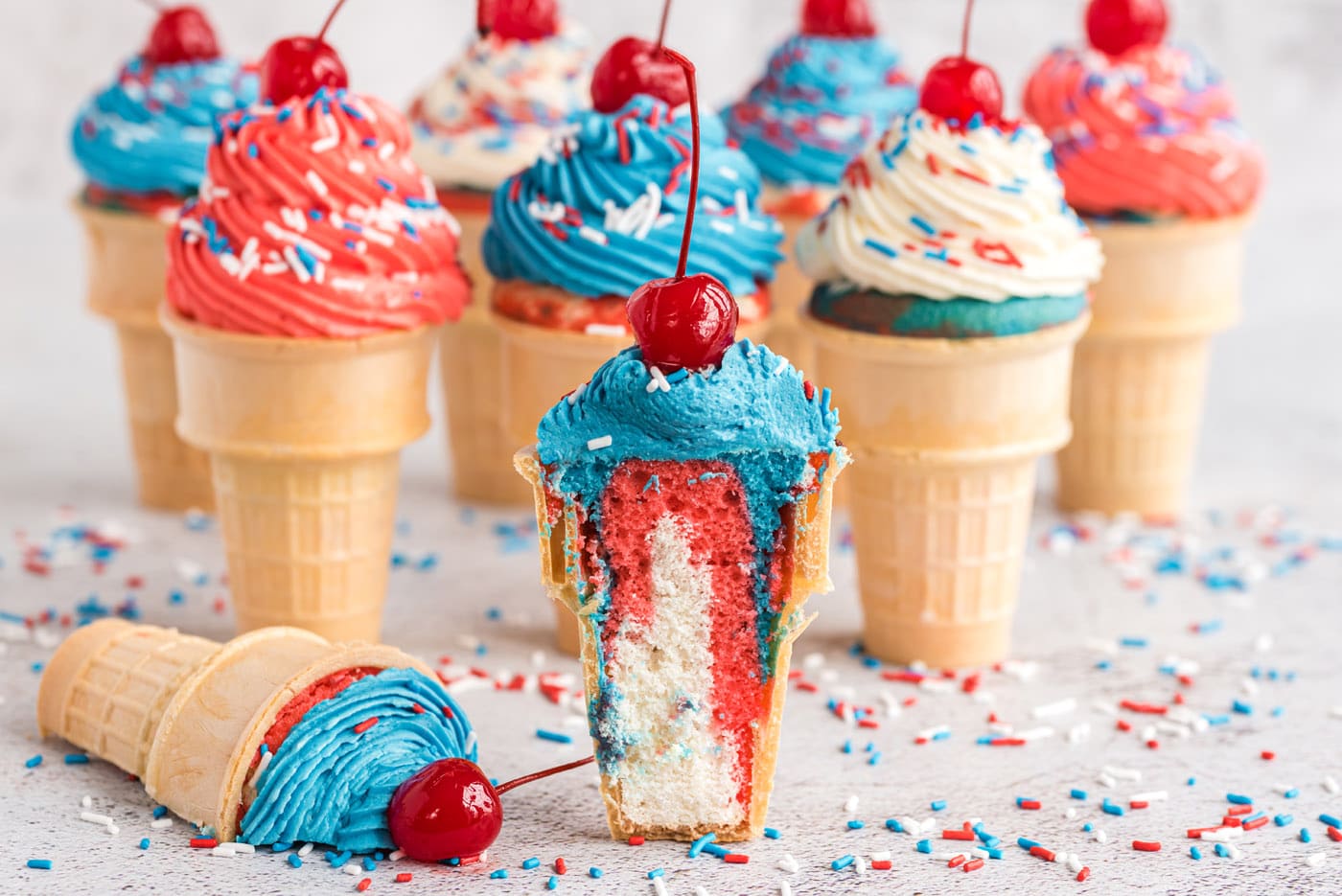 Pillowy buttercream frosting is piped on top of colorful red, white, and blue cake in a cone to mimi