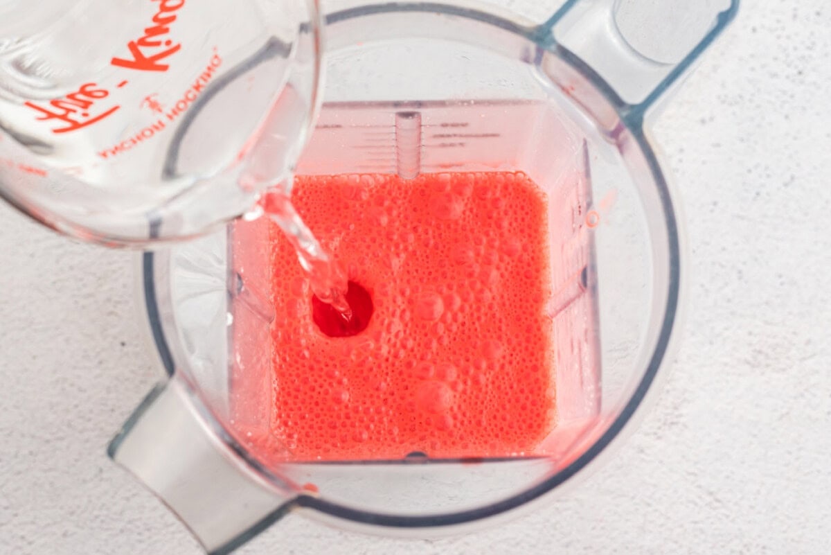 adding cold water to jello and cream cheese mixture in a blender