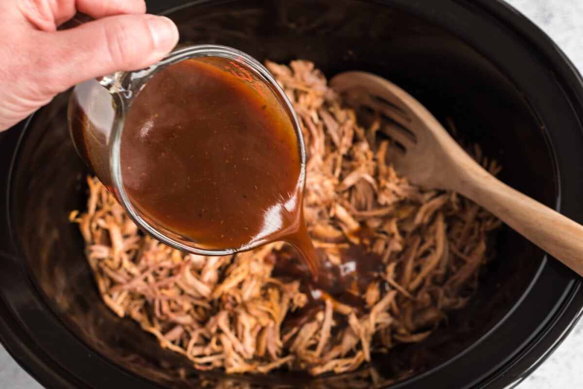 pouring sauce over pulled pork