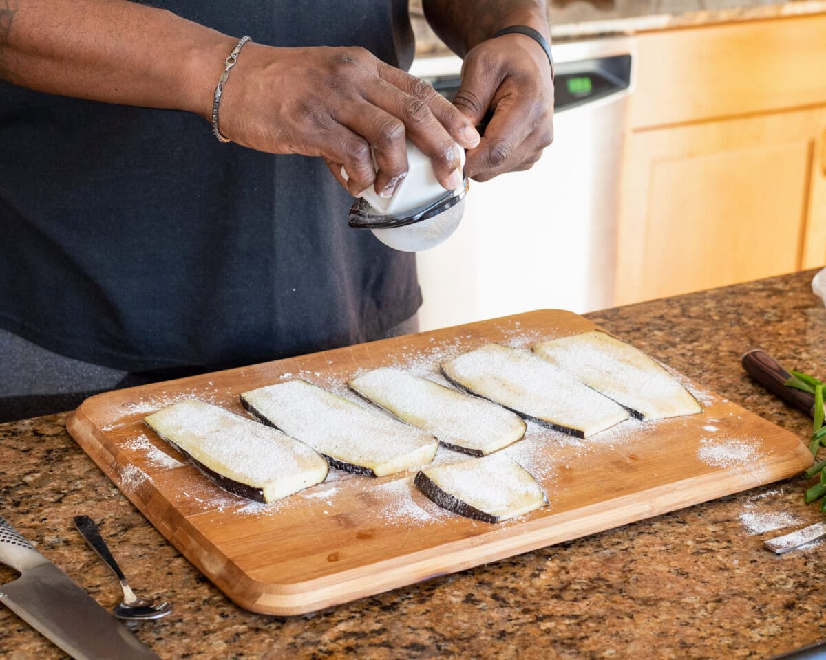 sifting cornstarch over slices of eggplant