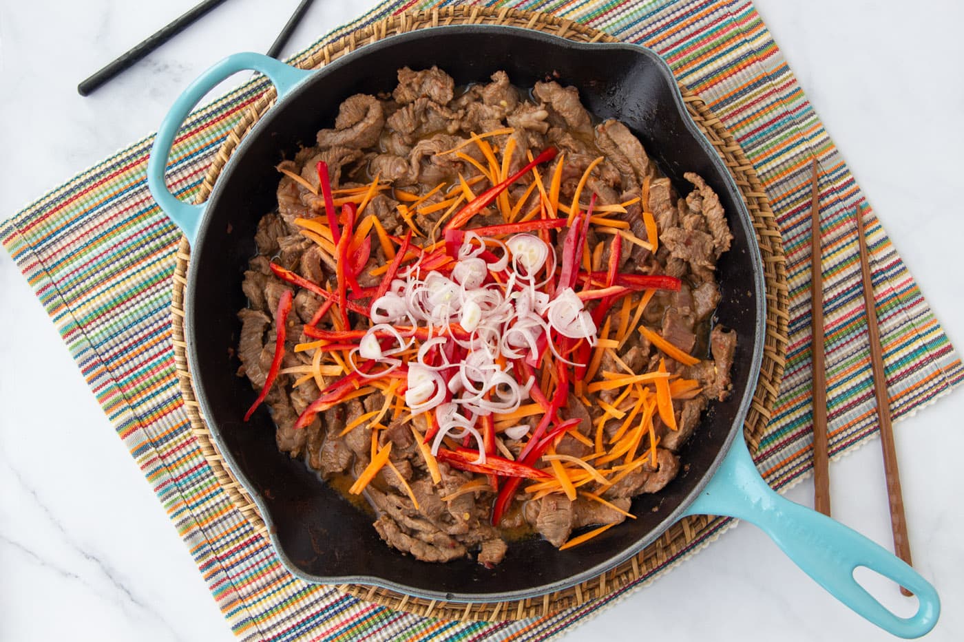 shallots, peppers, and carrots over beef in a skillet