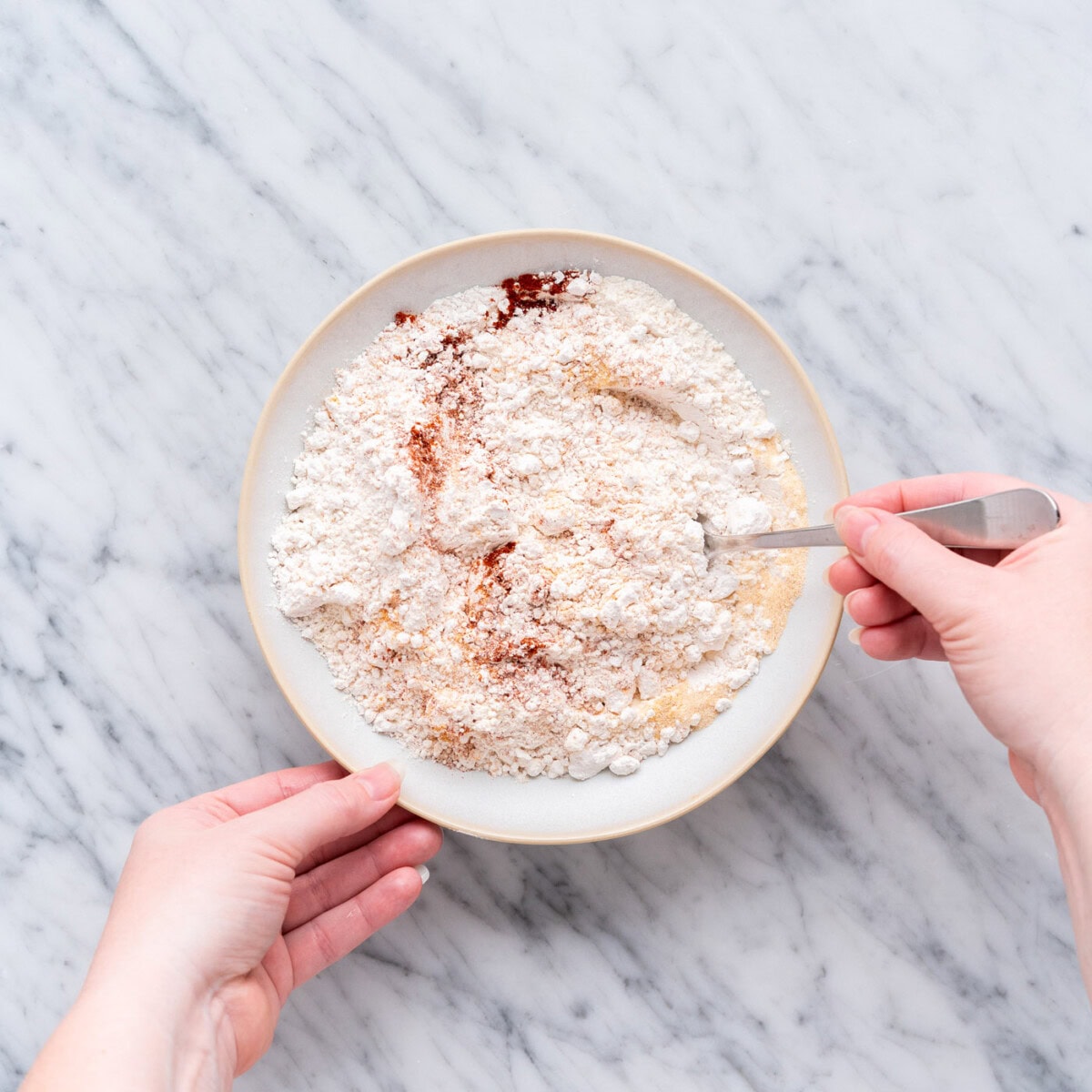 mixing seasoned flour in a shallow bowl