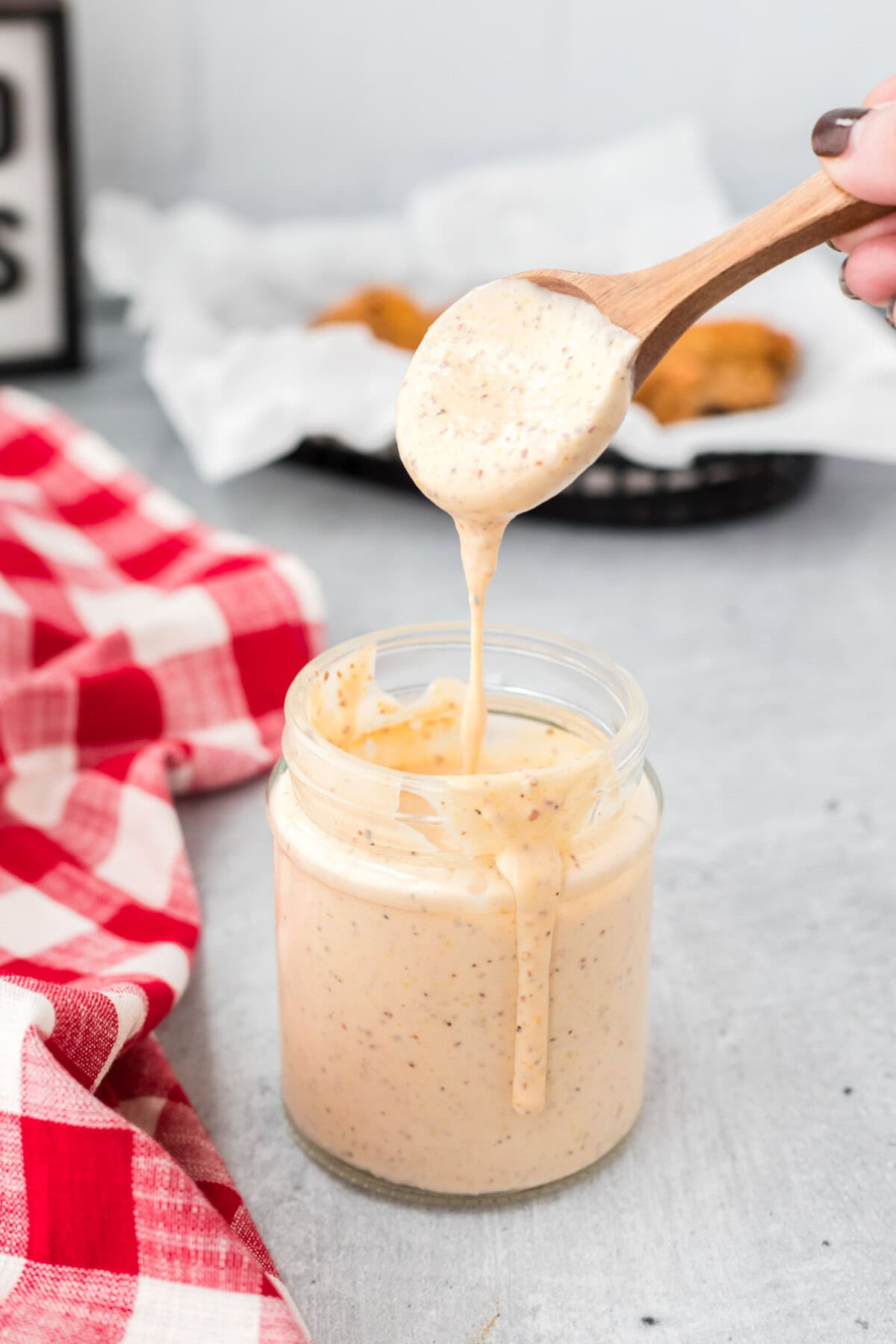 spoon dripping Alabama White Sauce into jar