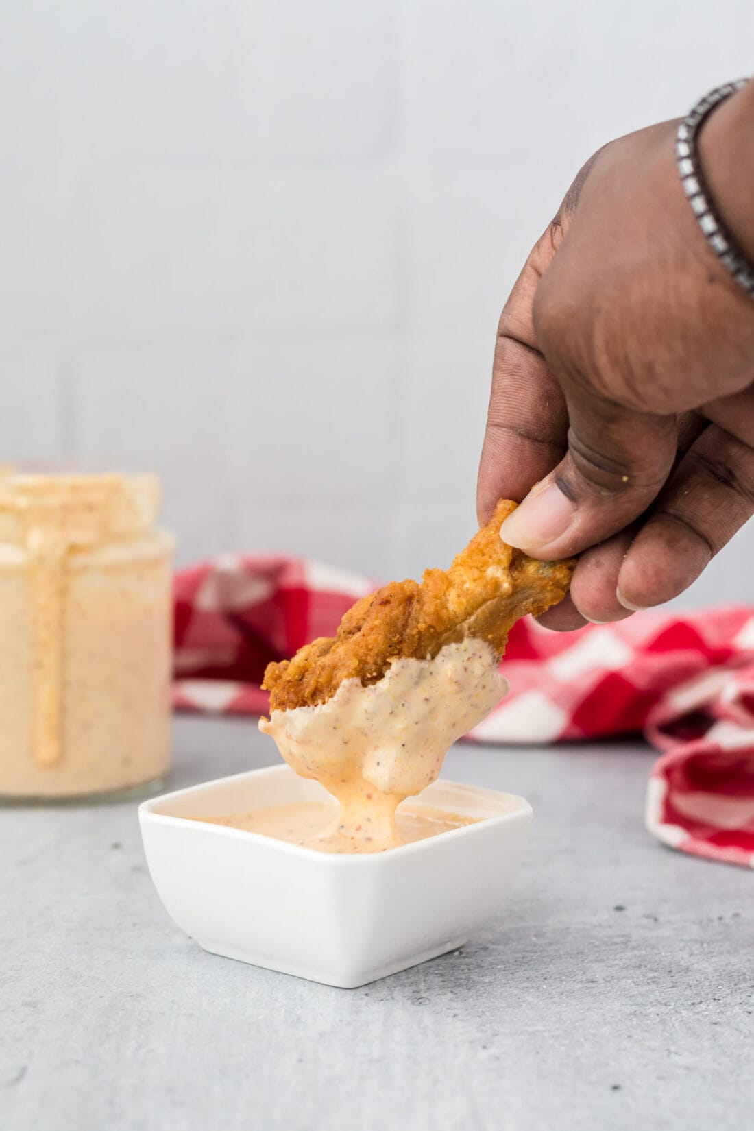dipping chicken wing into Alabama White Sauce
