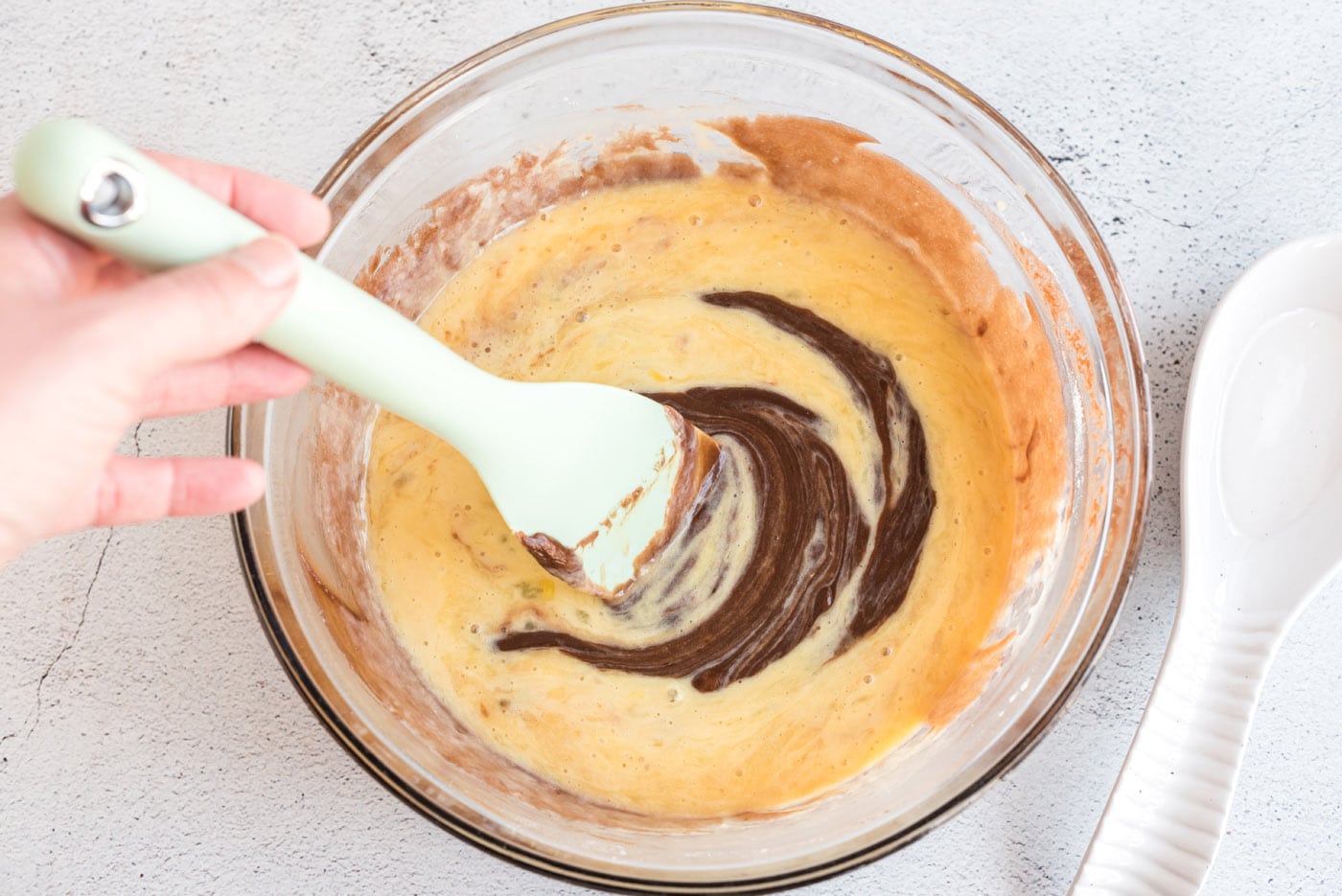 mixing sheet cake batter in a bowl with a spatula