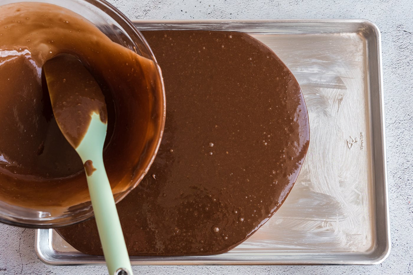 pouring chocolate sheet cake batter into a pan