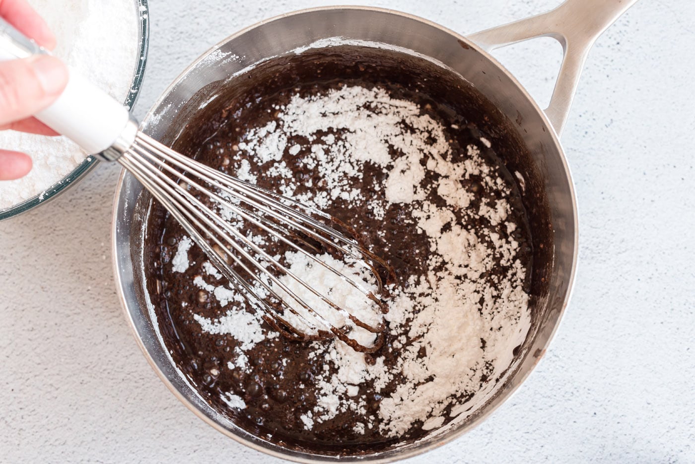 whisking chocolate fudge frosting in a saucepan